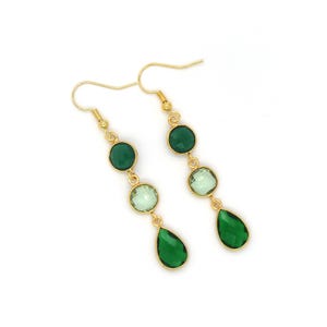 May include: Gold-coloured earrings with a gradient of green gemstones. Each earring has three gemstones: a round, a square, and a teardrop shape. The gemstones transition from dark to light green. The earrings have a hook closure.