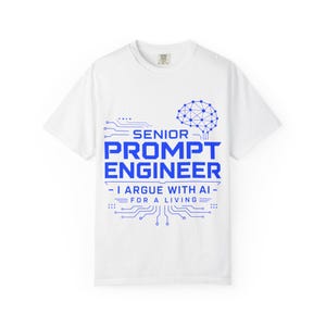Könnte beinhalten: Ein weißes Kurzarm-T-Shirt mit einer blauen Grafik eines Gehirns, das mit Leiterplattenlinien verbunden ist. Der Text lautet SENIOR PROMPT ENGINEER, I ARGUE WITH AI FOR A LIVING, umgeben von geometrischen Schaltkreismustern und Punkten.