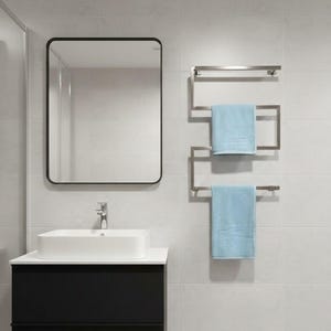 May include: A modern bathroom scene featuring a rectangular mirror with a black frame, a white rectangular sink atop a black cabinet, and a stainless steel towel rack with two light blue towels. The walls are tiled in a light gray color.