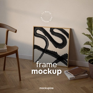 Può includere: Un mockup di stampa artistica incorniciata con uno sfondo beige e audaci pennellate nere. La cornice è di colore legno chiaro. Le parole "frame mockup" sono visualizzate in testo bianco. L'immagine è appoggiata a un muro accanto a una sedia di legno e una pianta in vaso.