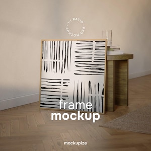Può includere: Un'opera d'arte incorniciata in legno con un design astratto in bianco e nero di tratti verticali e orizzontali. Le parole "frame mockup" sono stampate in bianco nella parte inferiore dell'opera. L'opera è appoggiata a un muro.