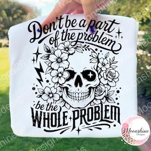 Op de afbeelding: Wit t-shirt met een zwart schedelontwerp versierd met bloemen en de tekst "Don't be a part of the problem, be the WHOLE PROBLEM." Het ontwerp bevat sterren en een bliksemschicht.