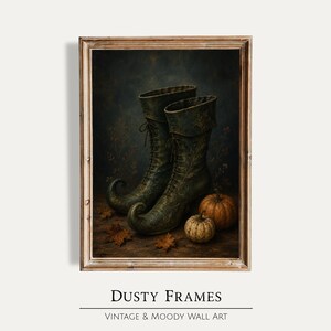 Pode incluir: Uma impressão de arte emoldurada apresentando um par de botas de amarrar verde-escuras com pontas curvadas, posicionadas ao lado de duas pequenas abóboras e folhas de outono espalhadas sobre uma superfície escura e texturizada, em uma moldura de madeira desgastada.