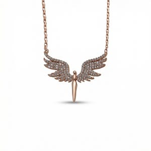 May include: Rose gold-toned necklace featuring an angel pendant. The pendant has outstretched wings encrusted with small, clear gemstones. The angel's body is a vertical, pointed shape. The chain is a delicate link style.