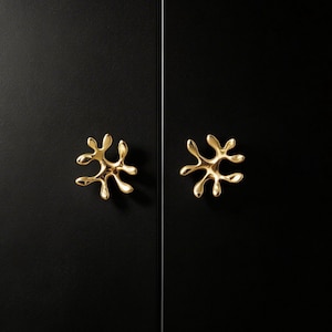 May include: A white ceramic mug with a black handle and the text "But First, Coffee" in a bold, black font. The mug is set against a blurred background, suggesting a cozy setting.