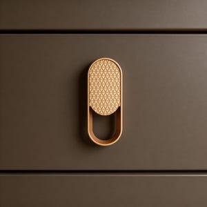 May include: A wooden cabinet pull with a geometric design. The pull is light brown and has a rounded rectangular shape with a curved handle. The background is a dark brown cabinet. The pull is likely made of wood.