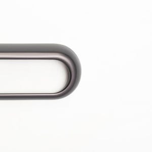 Pu&ograve; includere: Primo piano di una maniglia per mobili ovale grigio scuro con interno bianco. La maniglia ha un design liscio e arrotondato ed &egrave; posta su uno sfondo bianco. Questo hardware &egrave; adatto per cassetti e armadi.