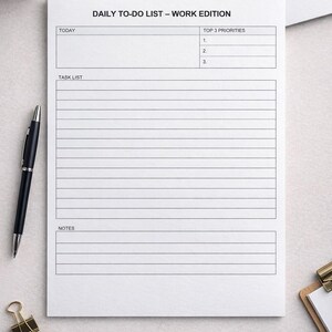 Può includere: Un blocco note bianco "Daily To-Do List - Work Edition". Include sezioni per "OGGI", "TOP 3 PRIORITÀ", "ELENCO COMPITI" e "NOTE". Sono visibili una penna nera, fermagli dorati e occhiali con montatura nera.