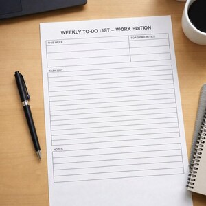 Può includere: Un elenco settimanale di cose da fare bianco intitolato "WEEKLY TO-DO LIST - WORK EDITION" con sezioni per la settimana, le priorità principali, l'elenco delle attività e le note. Una penna nera è appoggiata sulla superficie di legno accanto all'elenco.