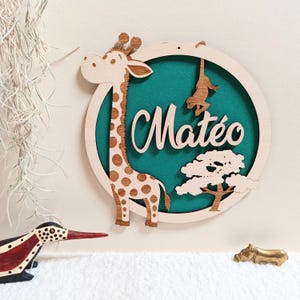 Peut inclure: Décoration murale en bois avec une girafe tachetée, un singe et un arbre, sur fond vert d'eau, dans un cadre circulaire. Le prénom "Matéo" est écrit en cursive. Parfait pour une chambre d'enfant. L'œuvre est en bois.