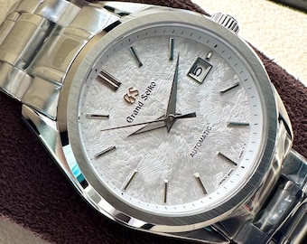 Reloj automático Sakura con esfera blanca texturizada y brazalete de acero inoxidable.