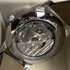 May include: A stainless steel wristwatch with an exhibition case back revealing the internal mechanical movement. The rotor is engraved with the Grand Seiko logo. Text on the case back includes 9SAS-0, MADE IN JAPAN, and WATER RESISTANT STAINLESS STEEL.