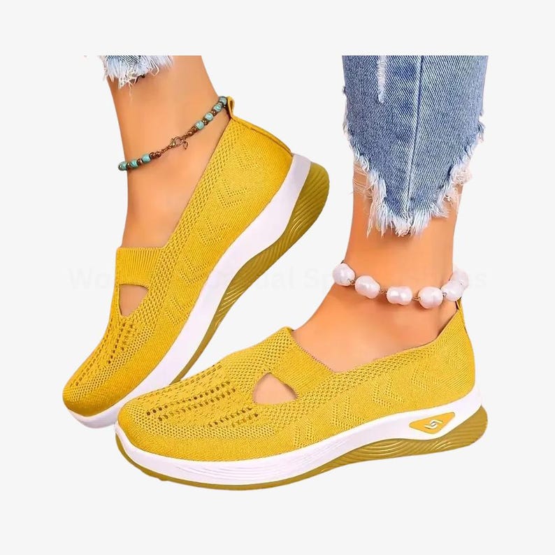 May include: Mustard yellow slip-on trainers with a breathable knit upper and a white sole. The shoes feature a cut-out detail on the side and a gold-coloured accent on the heel. Casual footwear.