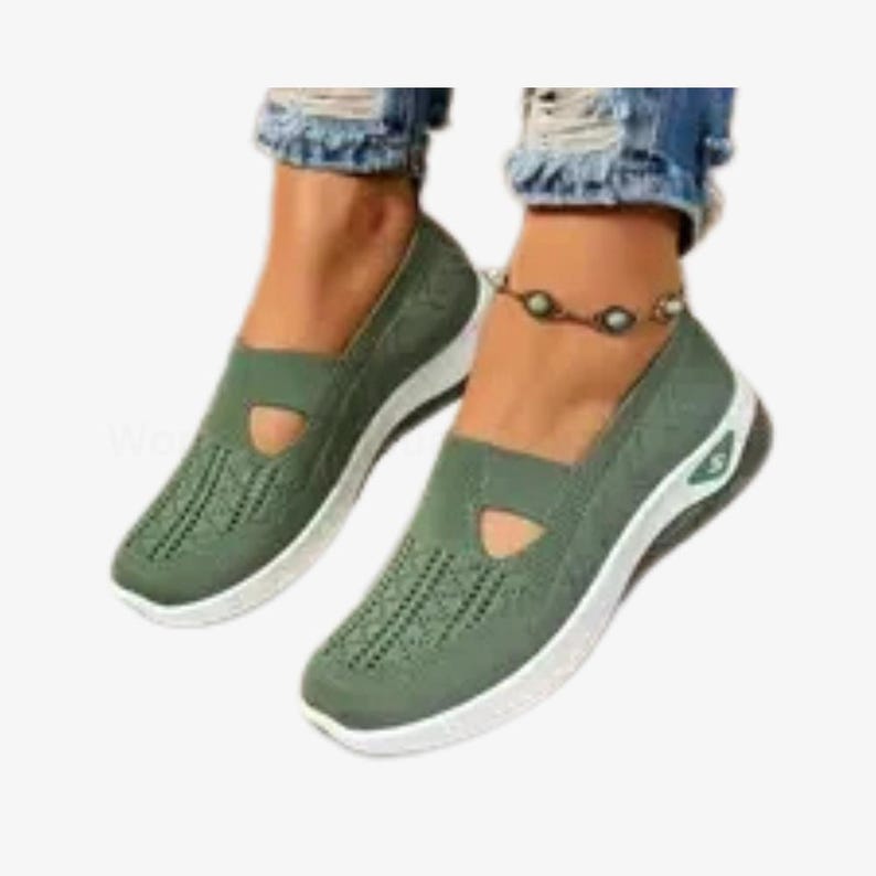 May include: Olive green slip-on shoes with a white sole and a small cutout detail. The shoes feature a textured pattern on the front and a small logo on the side. The shoes are designed for comfort.