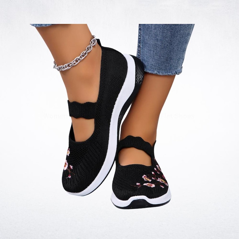 Pu&ograve; includere: Ballerine nere stile Mary Jane con suola bianca e design floreale. Queste scarpe hanno un cinturino smerlato e sono realizzate in tessuto a maglia traspirante. Offrono comfort e stile.