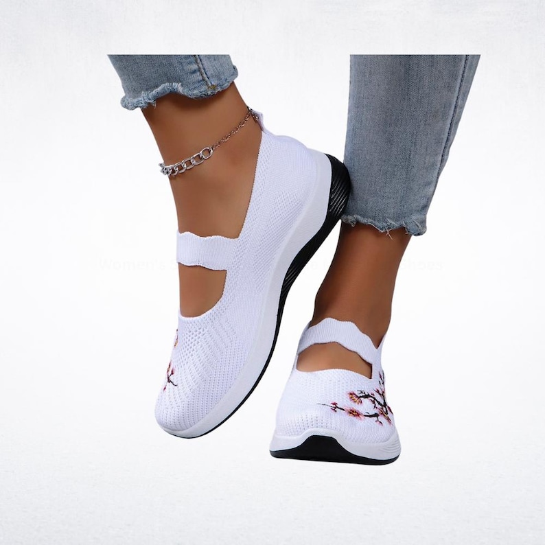 Pu&ograve; includere: Scarpe bianche in maglia stile Mary Jane con suola nera. Le scarpe presentano un ricamo floreale sulla punta. Le scarpe sono uno stile slip-on con un cinturino sulla parte superiore del piede.