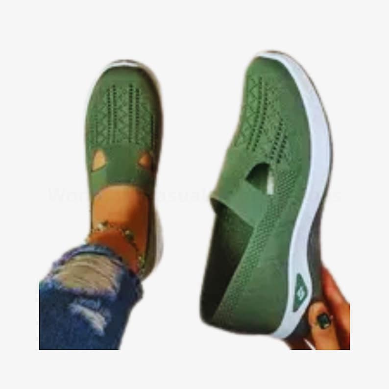 May include: Two green slip-on shoes with white soles. One shoe is on a foot, the other is held by a hand. The shoes have a breathable, woven design on the top.
