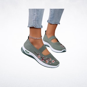 Pu&ograve; includere: Scarpe slip-on verde salvia con suola bianca e ricami floreali. Le scarpe hanno una tomaia in maglia traspirante e un cinturino sulla parte superiore del piede. Progettate per comfort e stile.