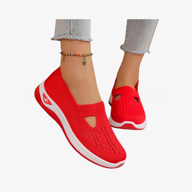 May include: Red slip-on trainers with a white sole and accents. The shoes feature a breathable knit upper and a cutout detail on the top. These trainers are designed for comfort and casual wear.
