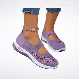Pu&ograve; includere: Sneakers in maglia lavanda con suole bianche e ricamo floreale. Le scarpe hanno un cinturino sulla parte superiore e una suola bianca. Comode, queste sneakers sono progettate per l'uso quotidiano.