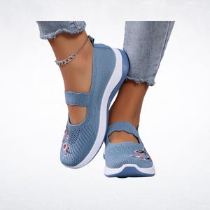 Pu&ograve; includere: Scarpe Mary Jane in mesh blu chiaro con suole bianche e ricami floreali. Le scarpe hanno un cinturino sulla parte superiore del piede e una punta arrotondata. Scarpe comode ed eleganti.