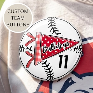 May include: A white baseball-themed button with black stitching and the text "Bulldogs" on a red pennant. The button also features the number 11 in black and the text "CUSTOM TEAM BUTTONS".