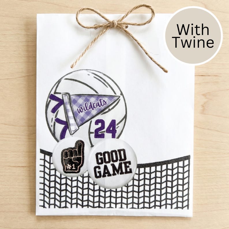 May include: A white gift bag tied with twine, featuring a volleyball design with a purple pennant that says "wildcats" and the number "24". Two round buttons say "#1" and "GOOD GAME". A black net design is at the bottom.