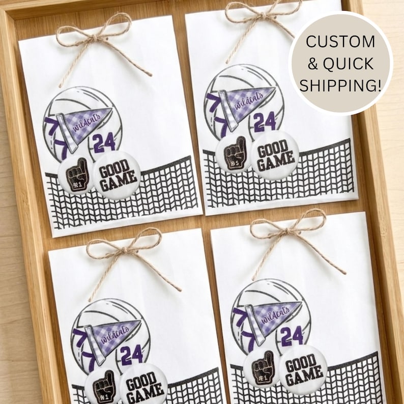 May include: Four white gift bags with a volleyball design, a pennant that says "wildcats", and the number "24". Each bag is tied with twine. The bags also have a "Good Game" button and a foam finger button.