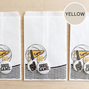 May include: White paper treat bags with a black and white net design at the bottom. Each bag features a sports-themed graphic with a basketball, a pennant that says "Tigers", and the number "20". White buttons with a foam finger and "Good Game" are also included.