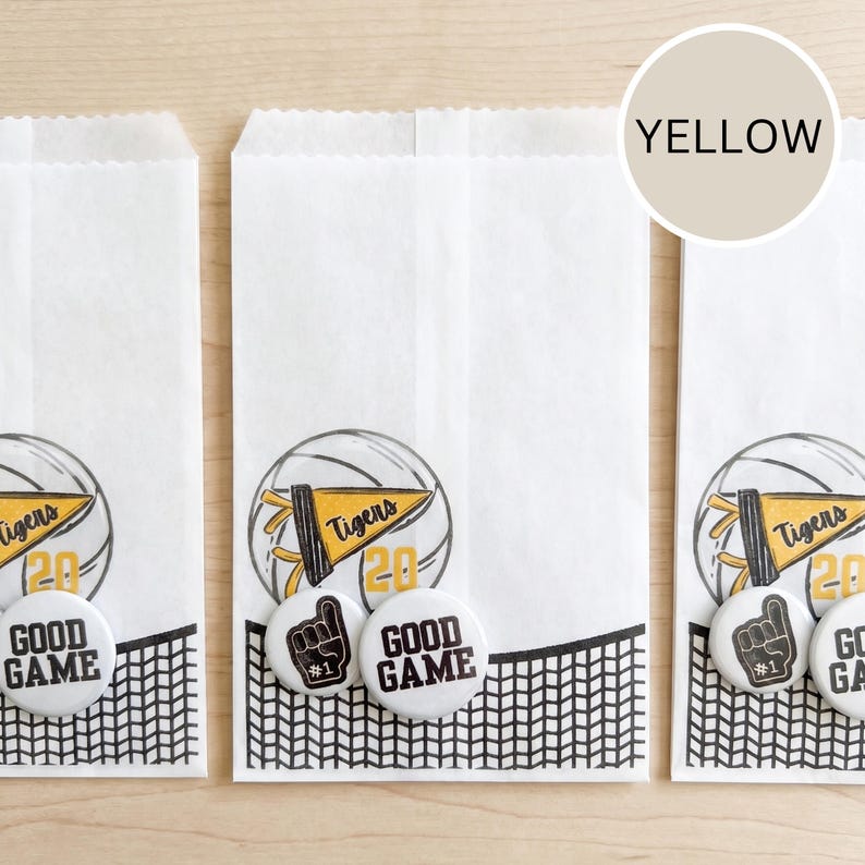 May include: White paper treat bags with a black and white net design at the bottom. Each bag features a sports-themed graphic with a basketball, a pennant that says "Tigers", and the number "20". White buttons with a foam finger and "Good Game" are also included.
