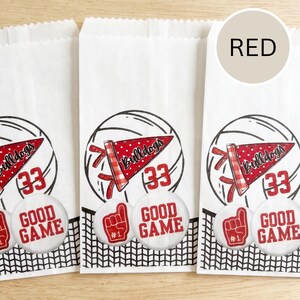 May include: White paper treat bags with a volleyball design. Each bag features a red pennant with "Bulldogs" and the number "33". Below, a button reads "GOOD GAME" and a foam finger. The word "RED" is in a circle.
