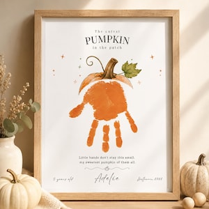 Op de afbeelding: Een ingelijste print met een aquarelillustratie van een pompoen met een oranje handafdruk in het midden. De tekst luidt: The cutest PUMPKIN in the patch, Little hands don't stay this small, my sweetest pumpkin of them all, Adelie, 3 years old, Halloween 2026.