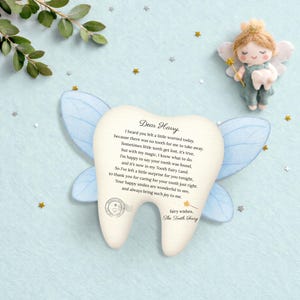 May include: A tooth-shaped plaque featuring a printed letter to Harry from the Tooth Fairy, accented by light blue fairy wings. The text reads: Dear Harry, I heard you felt a little worried today, because there was no tooth for me to take away.
