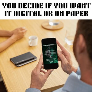 May include: A person holding a smartphone displaying a Quantum Gaming advertisement with the text "MORE FAST MORE POWERFUL BEST EXPERIENCE". The image also includes the text "YOU DECIDE IF YOU WANT IT DIGITAL OR ON PAPER". A notebook and a coffee cup are on the table.