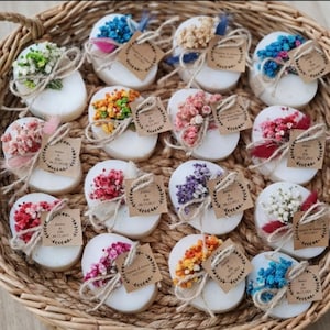 May include: A white ceramic mug with a black handle and the text "But First, Coffee" in a black, handwritten-style font. The mug is on a white surface.