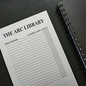 Könnte beinhalten: Ein weißes Blatt Papier mit der Überschrift THE ARC LIBRARY, horizontalen Linien für Buchtitel und drei runden Kästchen mit der Beschriftung FINISHED, KEEP und PASS ON, neben einem schwarzen Spiralblock auf einer dunklen Oberfläche.