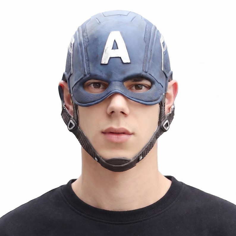 May include: A blue Captain America helmet with a white "A" on the forehead. The helmet has a chin strap and eye openings. The person in the image is wearing a black shirt.
