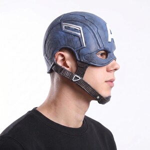 May include: A blue Captain America helmet with a white "A" on the forehead. The helmet has silver accents and a chin strap. The mask covers the eyes and nose. The helmet is a costume accessory.