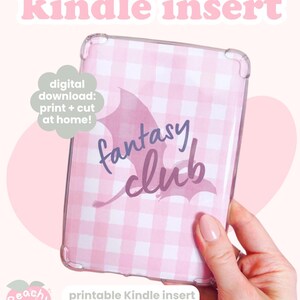 Puede incluir: Una funda Kindle a cuadros rosas y blancos con las palabras "fantasy club" en escritura púrpura. Las palabras "descarga digital" e "inserto Kindle" están en la parte superior. Las palabras "descarga digital: ¡imprime + corta en casa!" están en forma de nube.