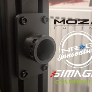 Könnte beinhalten: Schwarzes Metallbauteil mit zylindrischer Öffnung, befestigt mit vier Schrauben an einer schwarzen vertikalen Struktur. Das Bild zeigt die Logos von MOZA Racing, NRG Innovations, SIMAGIC und CAMMUS.
