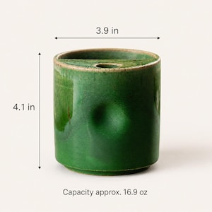 May include: A green ceramic container with a capacity of approximately 16.9 oz. The container is 4.1 inches tall and 3.9 inches wide. It has a small opening at the top and a slightly textured surface.