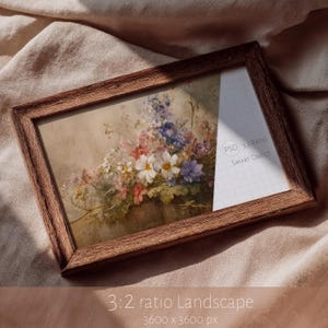 Puede incluir: Un marco de fotos rectangular de madera que contiene una pintura floral con flores blancas, rosas y azules. El lado derecho del marco muestra una cuadrícula blanca con el texto PSD 3:2 RATIO SMART OBJECT impreso en una insignia circular.