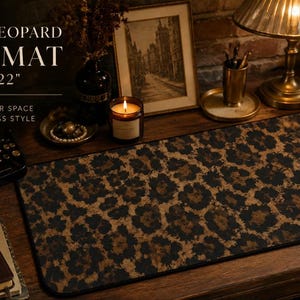 May include: A rectangular desk mat featuring a brown and black leopard print pattern, measuring 12 inches by 22 inches. The text on the image reads: VINTAGE LEOPARD DESK MAT 12" x 22" ELEVATE YOUR SPACE WITH TIMELESS STYLE.