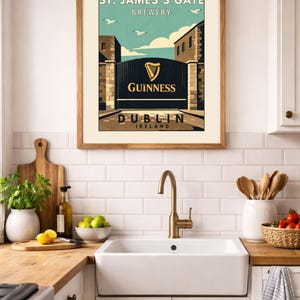 May include: Framed print featuring a vintage-style advertisement for St. James's Gate Brewery in Dublin, Ireland. The artwork showcases the Guinness logo and a gate scene with a blue sky and birds. The print is displayed in a kitchen setting.