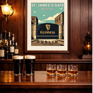 May include: A framed print of the St. James's Gate Brewery in Dublin, Ireland, with the Guinness logo. Two pints of Guinness and three glasses of whiskey sit on a wooden bar. The scene is set in a pub with dark wood paneling.