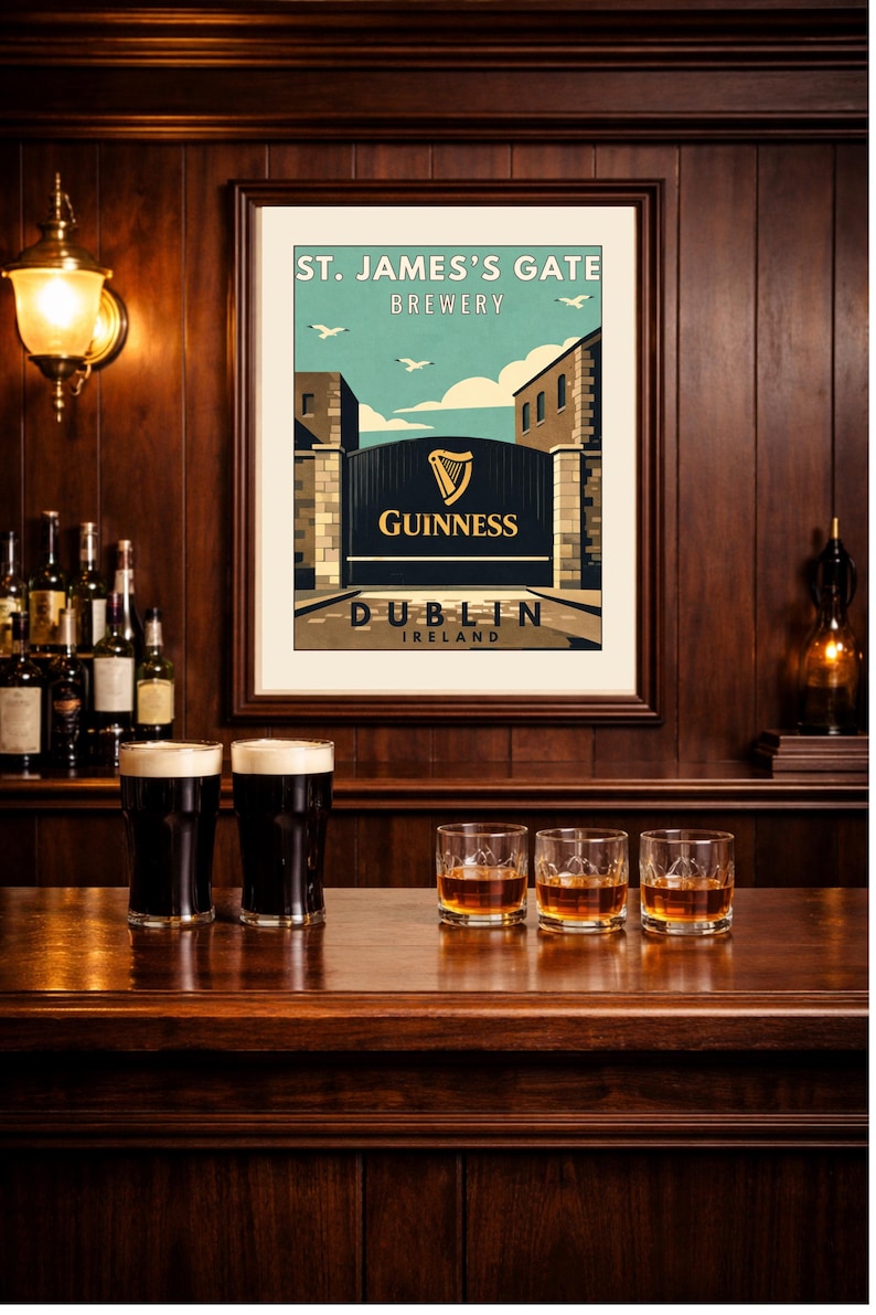 May include: A framed print of the St. James's Gate Brewery in Dublin, Ireland, with the Guinness logo. Two pints of Guinness and three glasses of whiskey sit on a wooden bar. The scene is set in a pub with dark wood paneling.