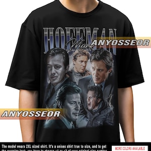 May include: Black t-shirt featuring a collage of Mark Hoffman images with the name "HOFFMAN" in a stylized font. The shirt includes the text "ANYOSSEOR" and "MORE COLORS AVAILABLE". The model wears a 2XL shirt.