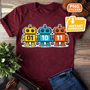 May include: Maroon t-shirt featuring three cartoon robots in yellow, blue, and orange. Each robot has a number: 01, 10, and 11. The shirt includes a "PNG Sticker" and "Instant Download" graphic.