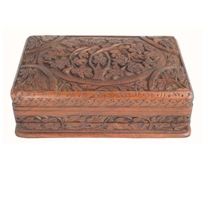 May include: A rectangular wooden box with intricate floral carvings. The box is a warm brown color and features detailed relief patterns on the lid and sides, showcasing a tree and leaf design. The box is likely used for storage.