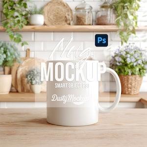 Puede incluir: Una taza de cerámica blanca con un asa curvada, colocada sobre una superficie de madera. La taza tiene las palabras "Mug MOCKUP" y "SMART OBJECT PSD". El fondo muestra una cocina con plantas y estantes.